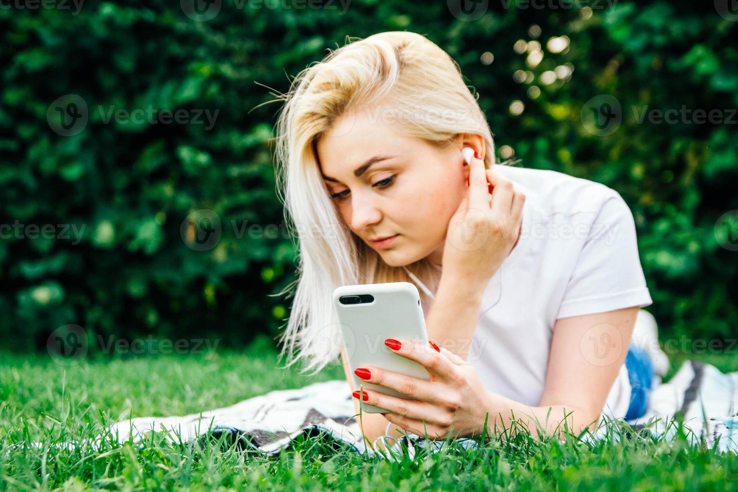 Woman in headphones and smartphone in hands listens to music photo