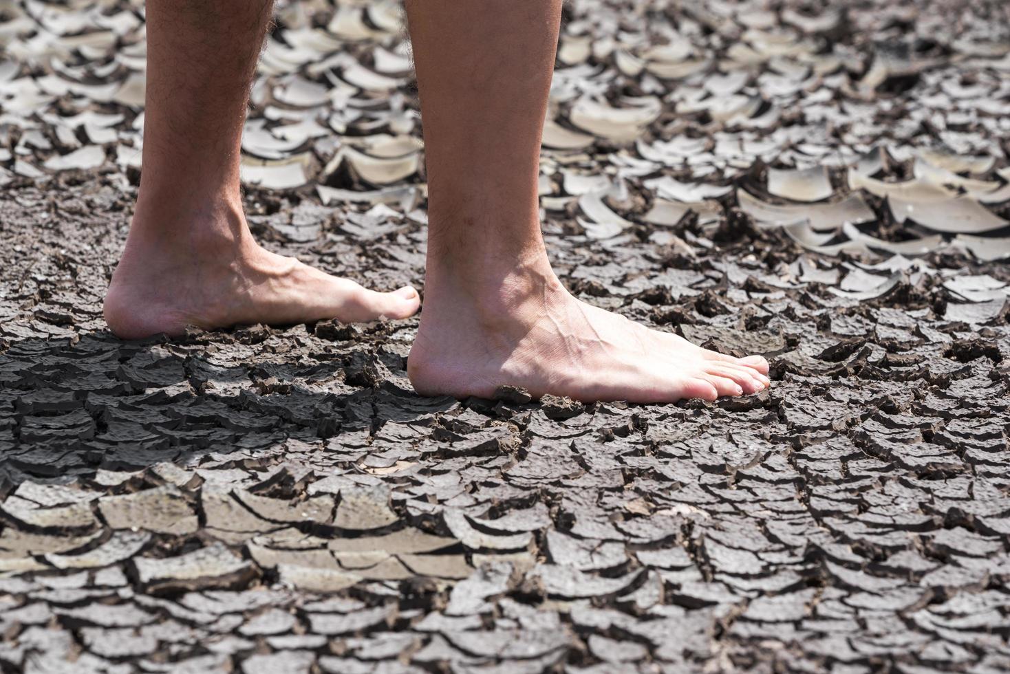 bare feet of a person on dry soil without plants close up photo