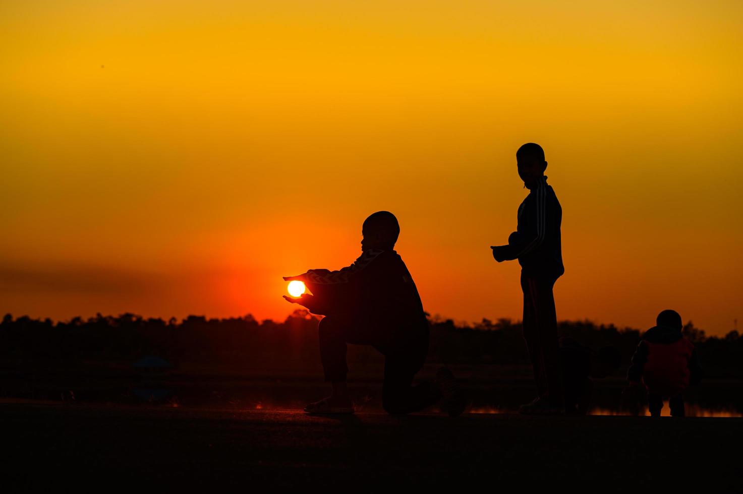 Child silhouette playing fun with many friends and playing against the sunset photo