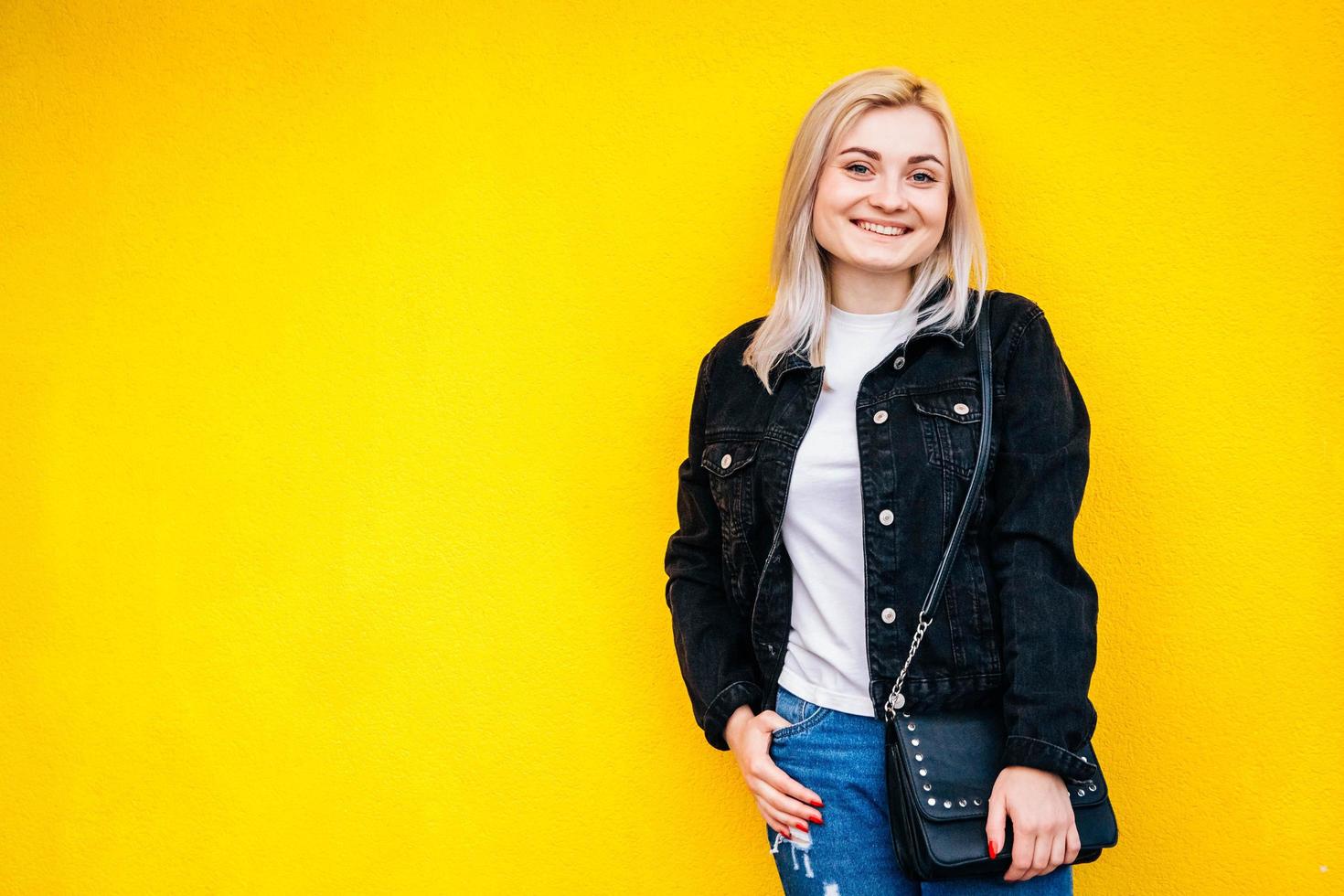 Woman in black jacket smiling posing on yellow background photo