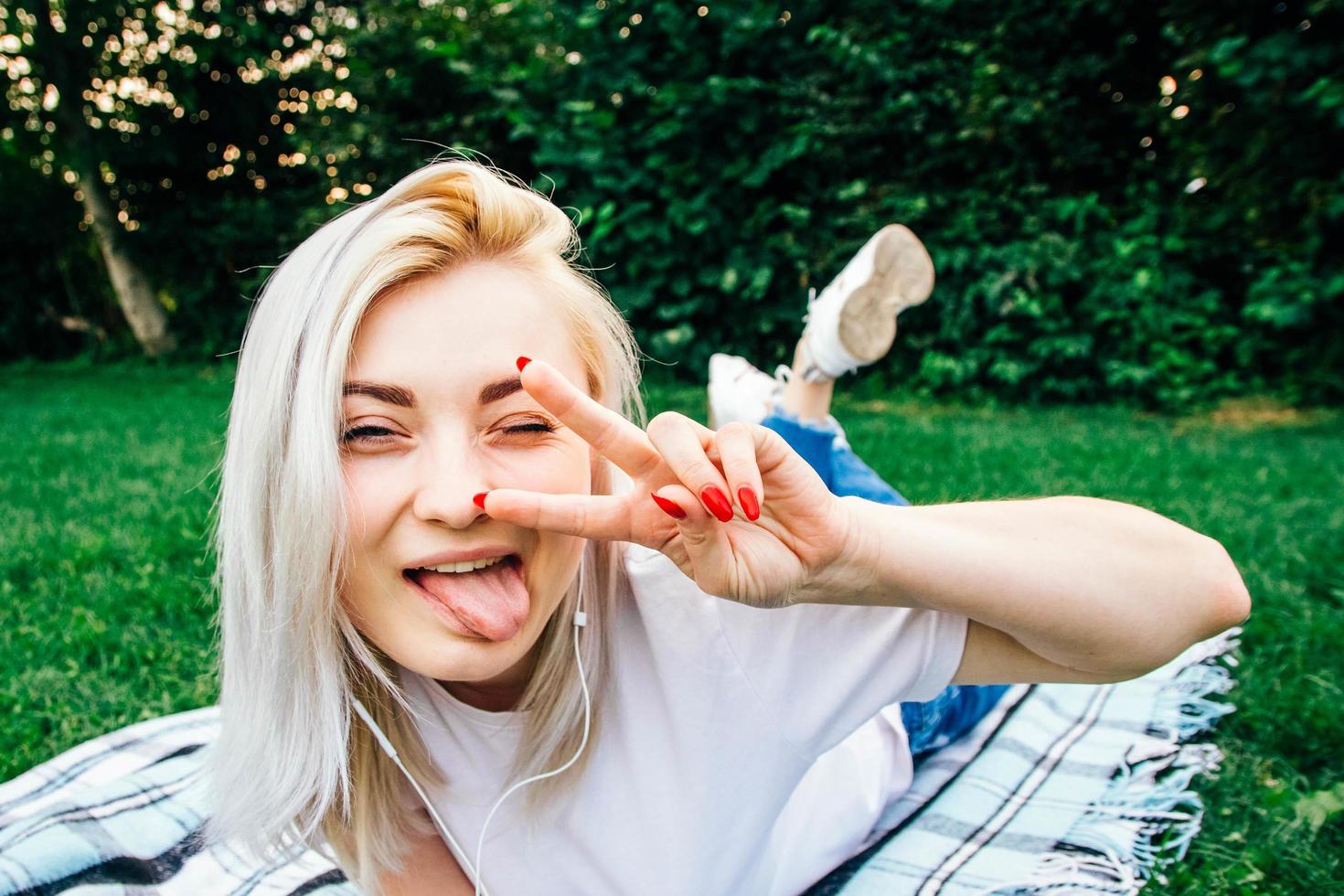 Crazy woman in headphones listens to music showing peace gesture photo