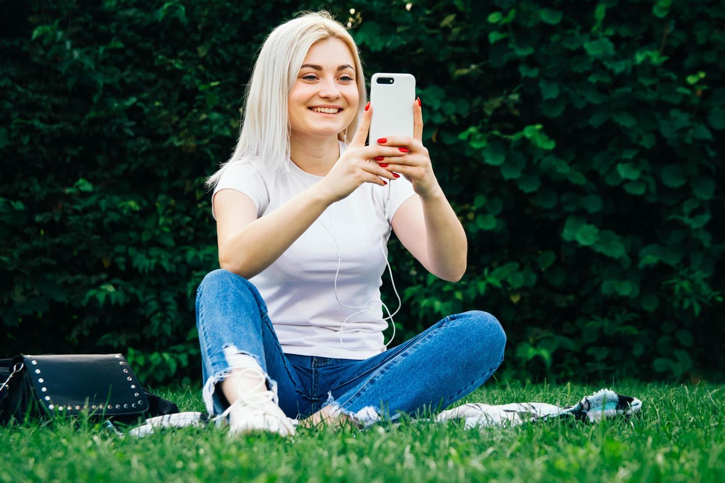 Woman in headphones and smartphone on green grass photo