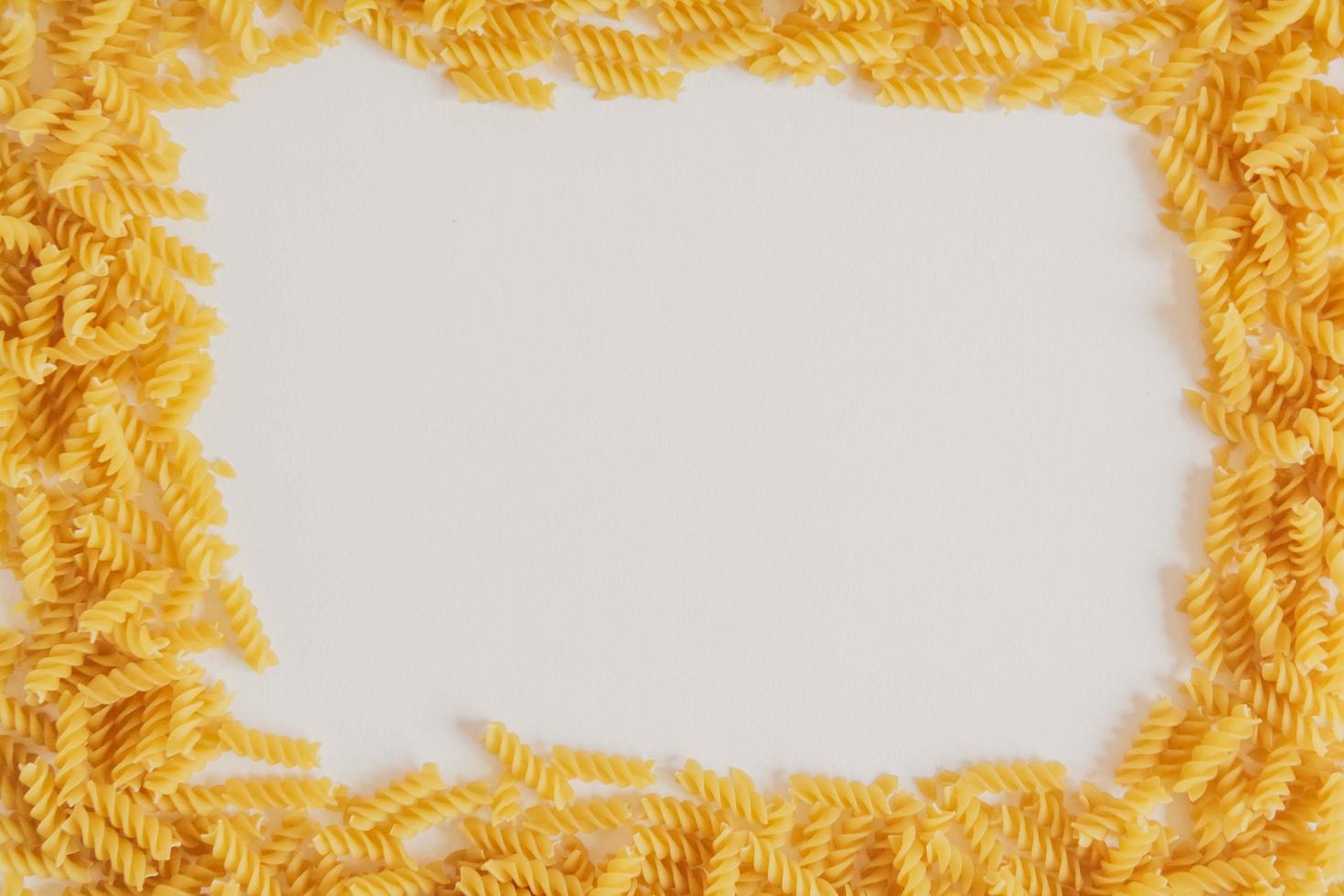 Spiral pasta on a white background forming a frame around photo