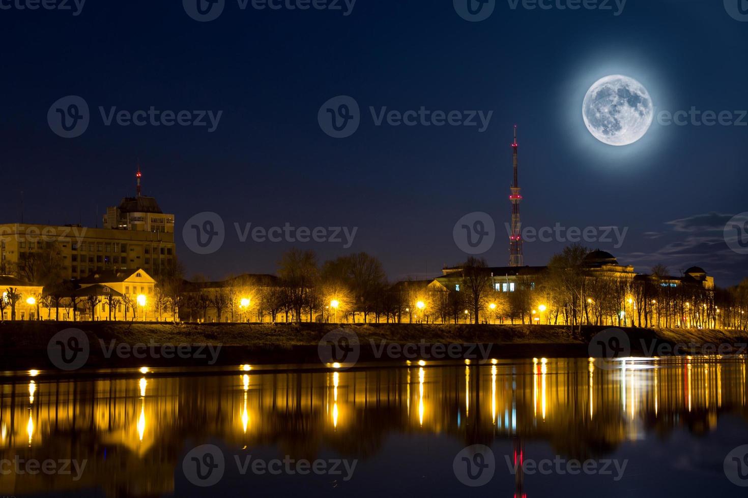 Full moon over the city. Night landscape. Lantern lights are reflected in water. Supermoon. photo