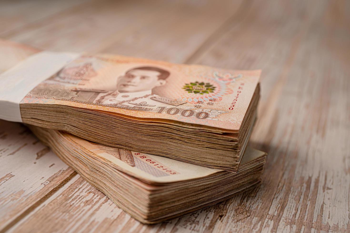 Stack of Thai baht banknotes on wooden background, business saving finance investment concept. photo