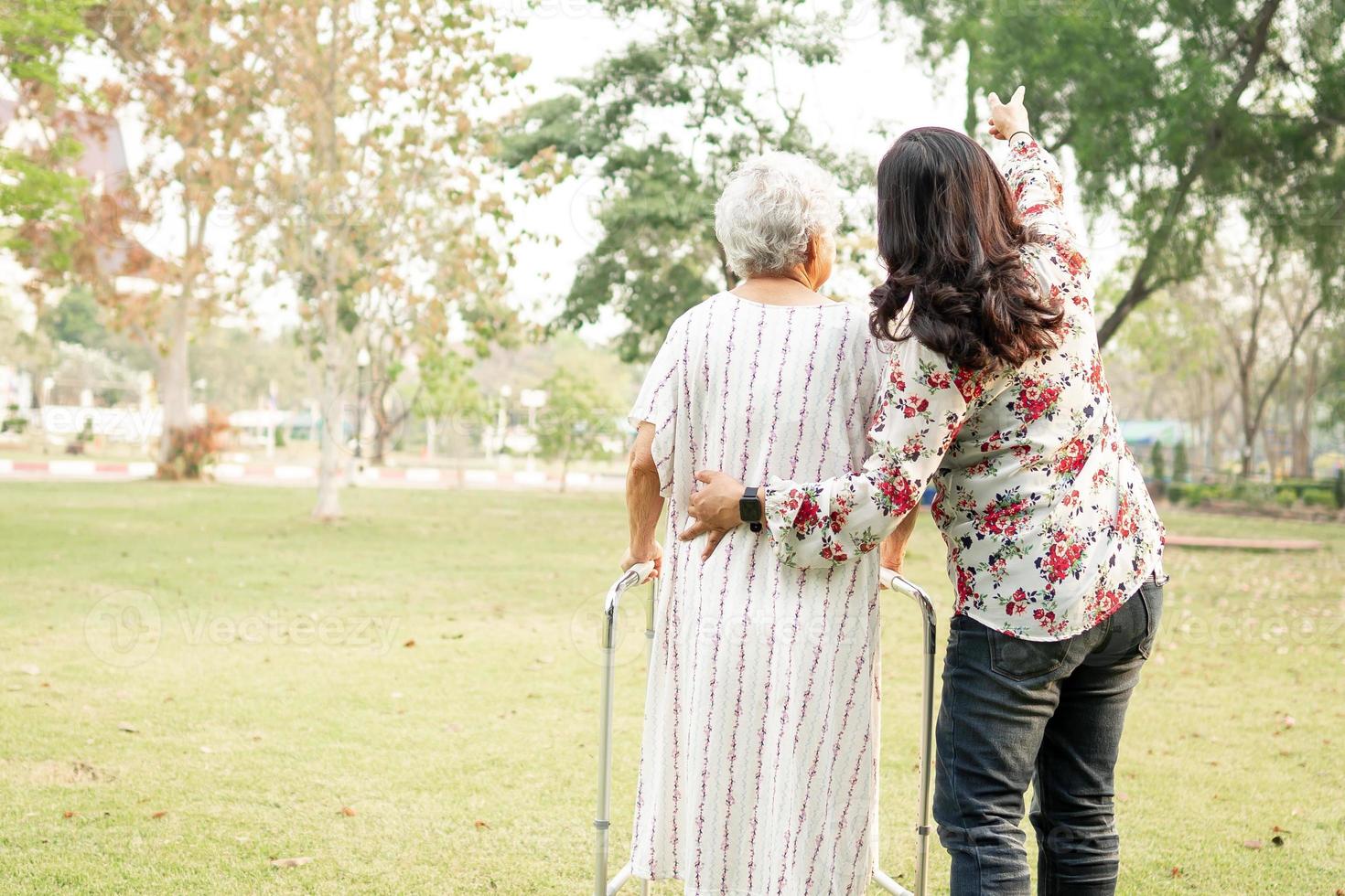 Ayude y cuide a la anciana asiática mayor o anciana que use un andador con una salud fuerte mientras camina en el parque en felices vacaciones frescas. foto