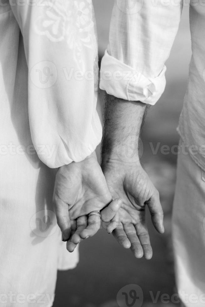 the bride and groom tenderly hold hands between them love photo