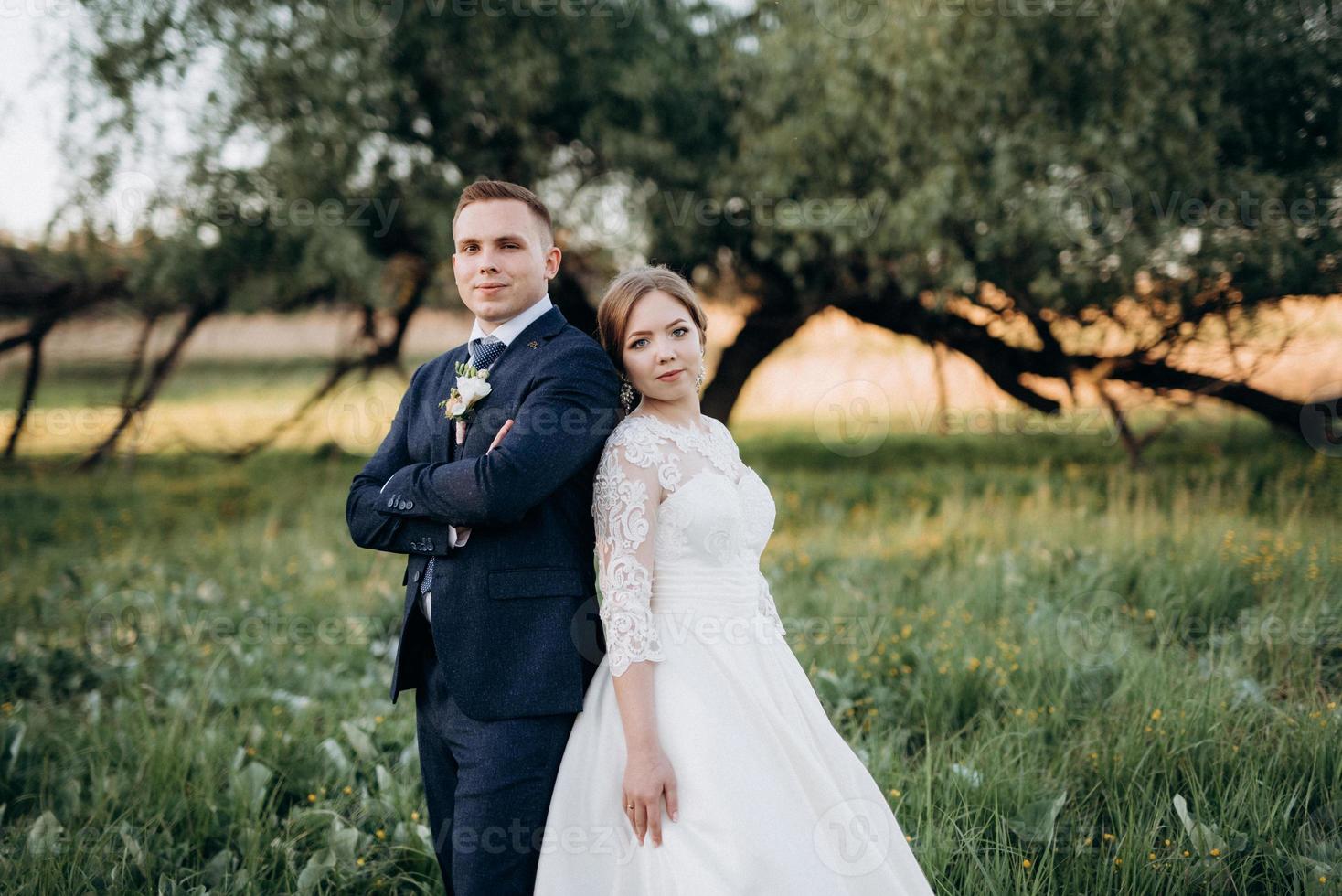 the groom and the bride are walking in the forest near a narrow river photo