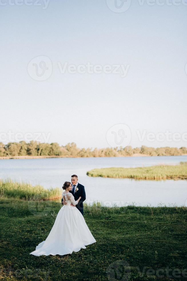 the groom and the bride are walking in the forest near a narrow river photo