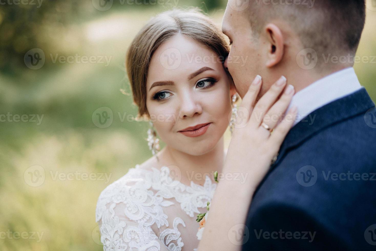 the groom and the bride are walking in the forest near a narrow river photo