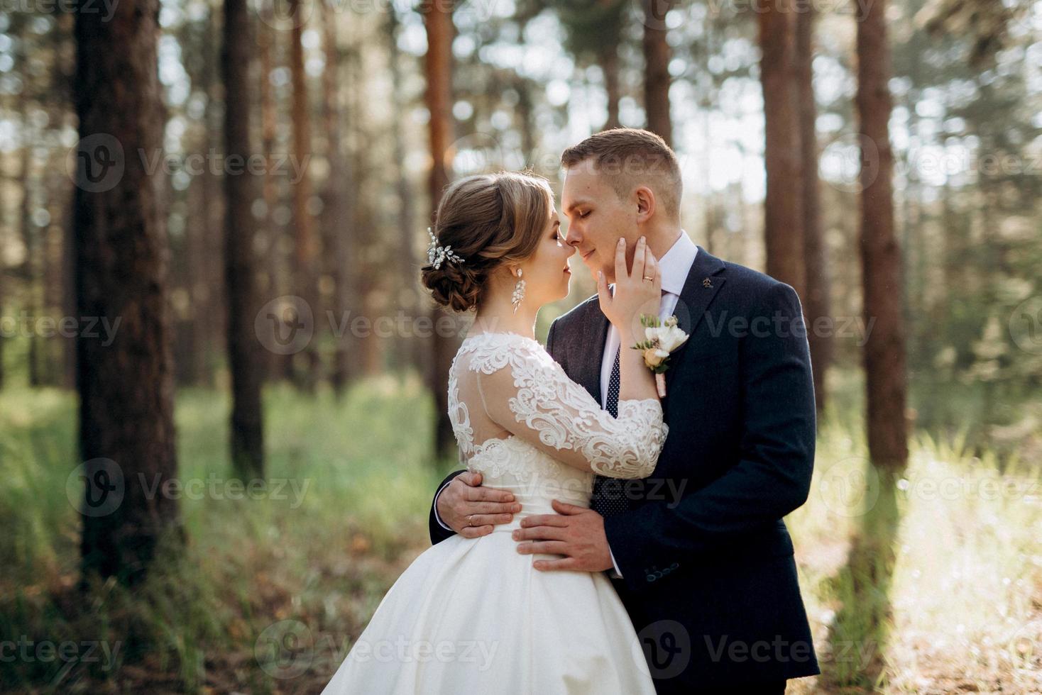 the bride and groom are walking in a pine forest photo