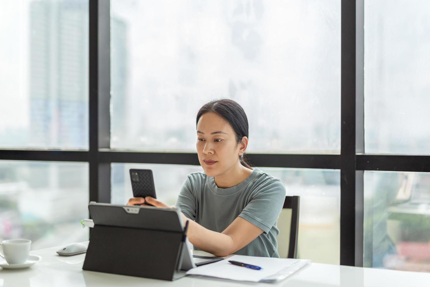 Beautiful woman video call on cell phone while during work on laptop. photo