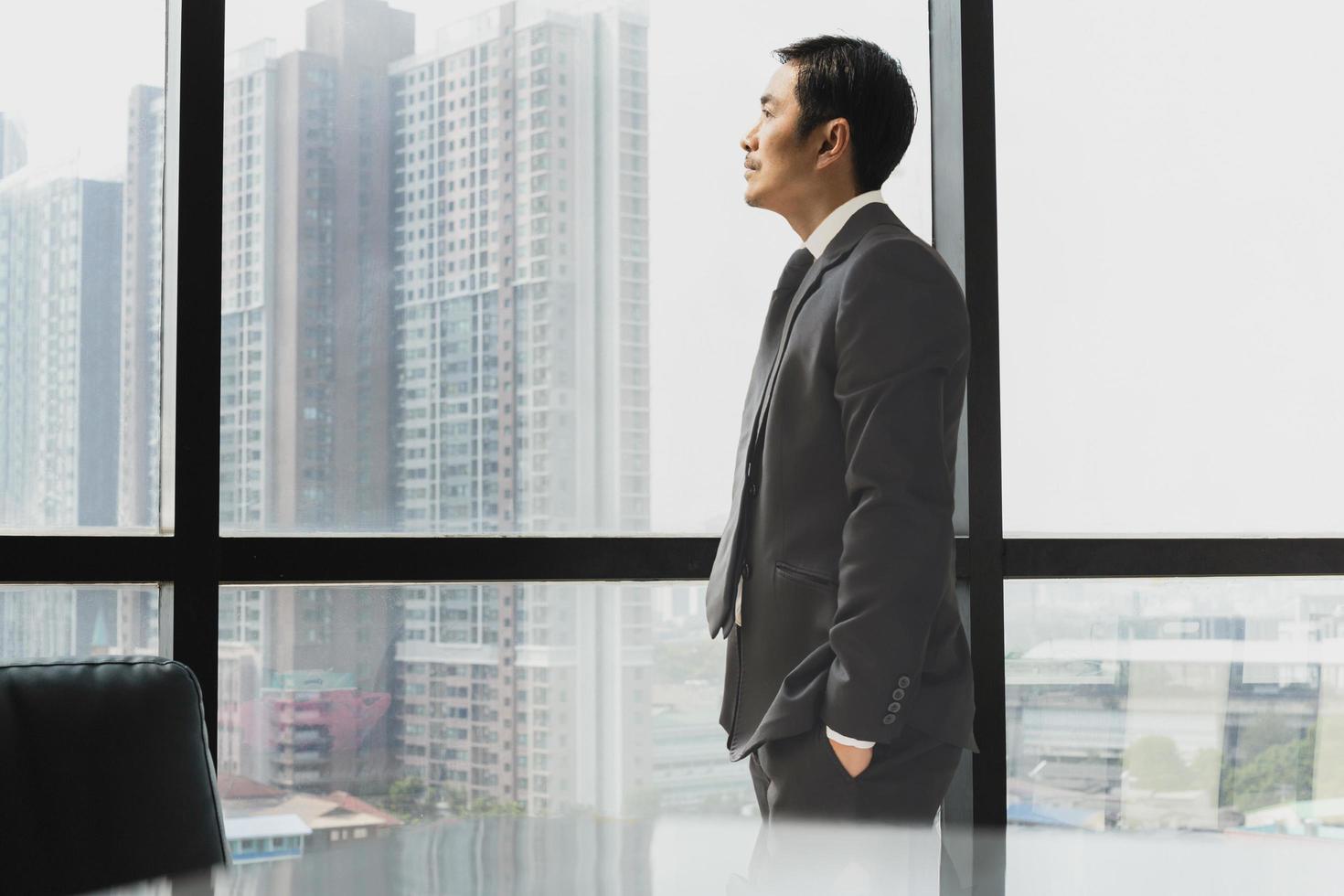 hombre de negocios de pie junto a la ventana mirando hacia la vista lateral. foto