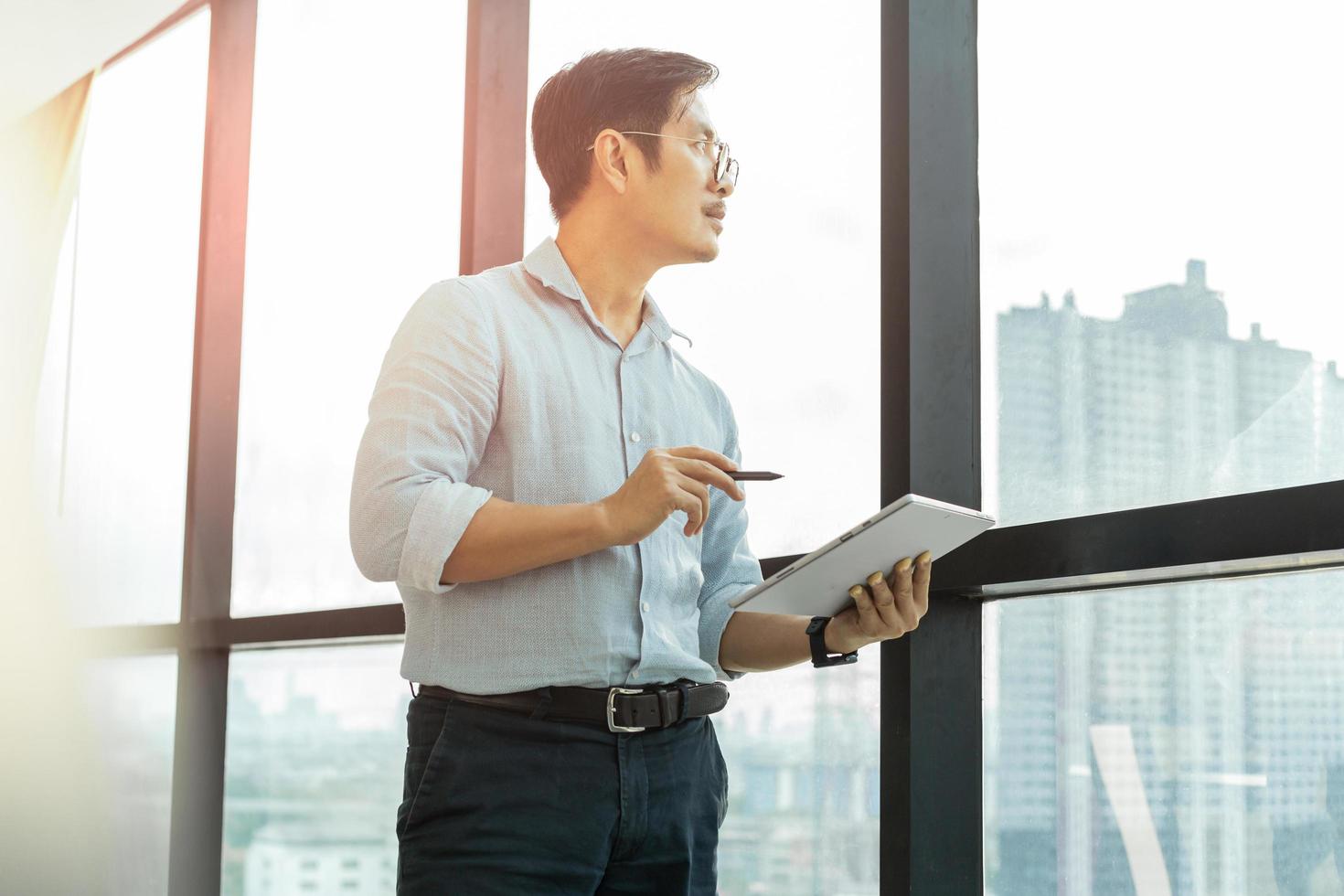 Businessman working with digital tablet while standing next to office window. photo