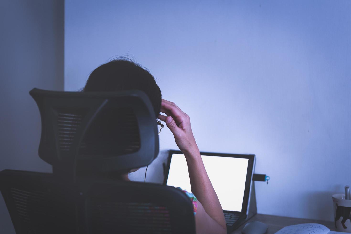 Destacó la mano de la empresaria en la cabeza trabajando en la computadora portátil a altas horas de la noche. foto