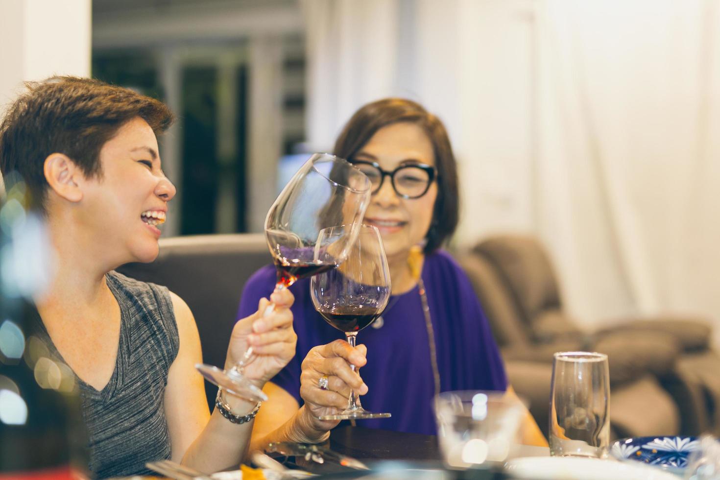 Happy family daughter toasting glasses of red wine with mother at home. photo