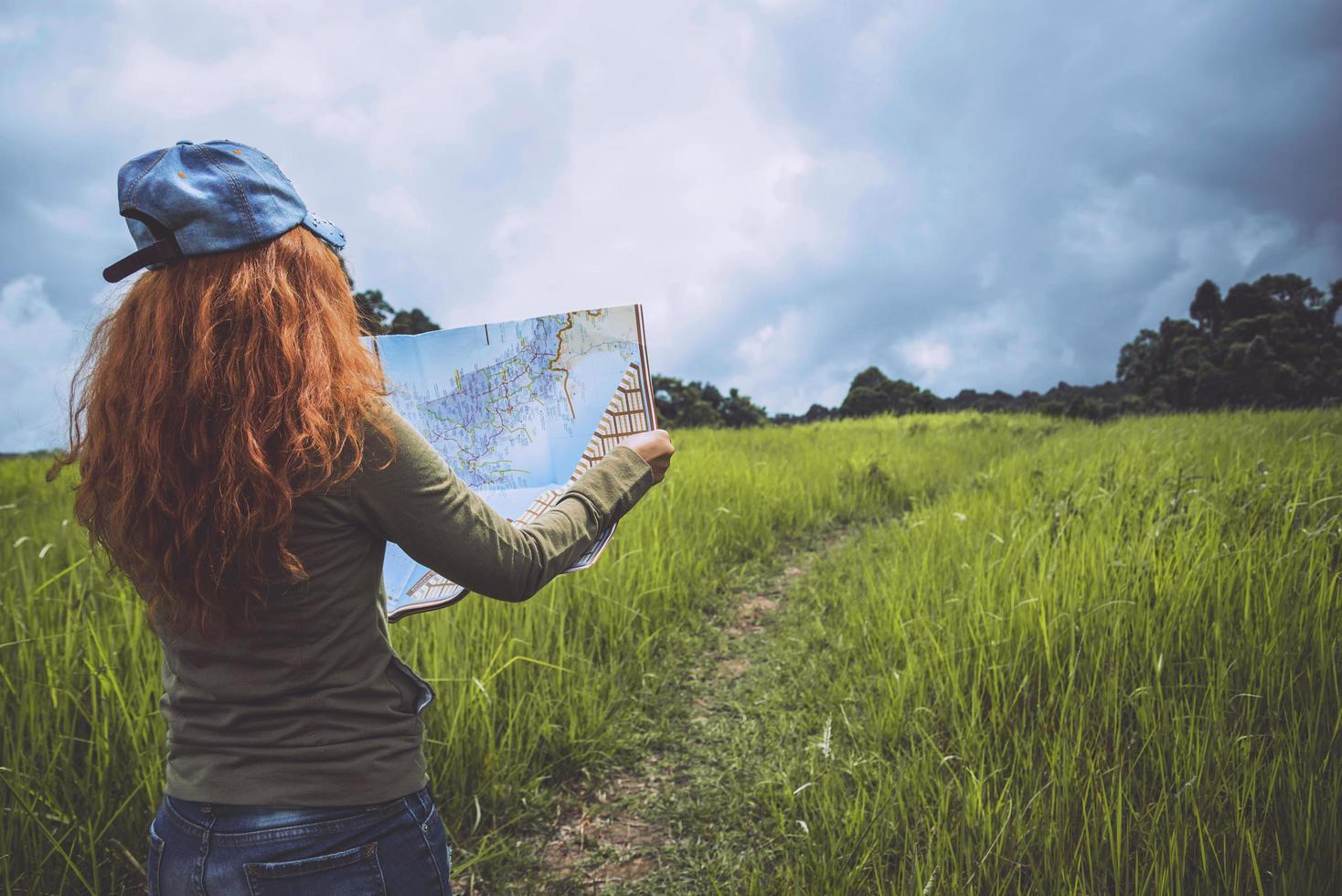 viaje de mujer. Las mujeres asiáticas ver mapa viajes naturaleza en la pradera foto