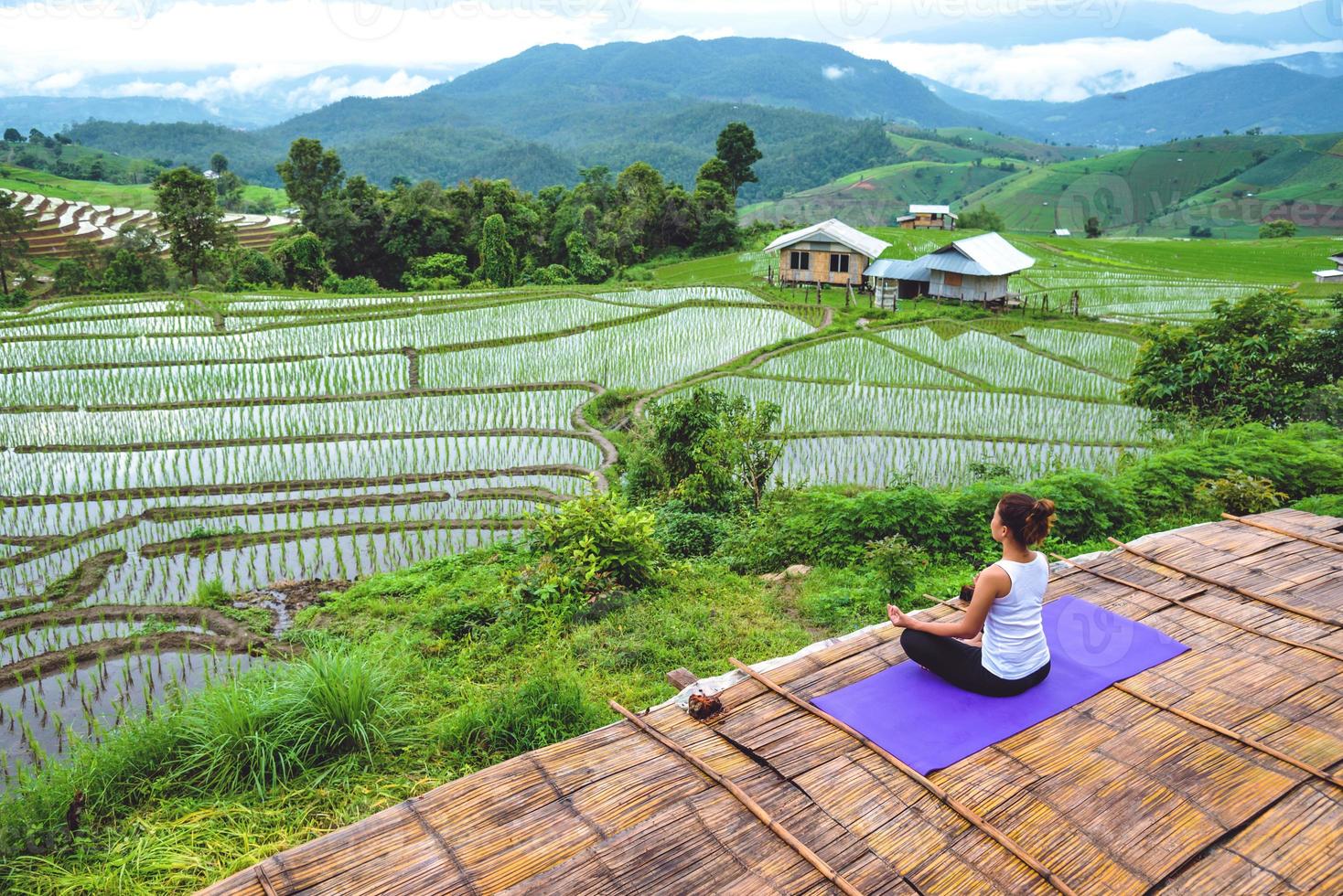 mujer asiática relajarse en las vacaciones. jugar si yoga. en el balcón paisaje campo natural foto