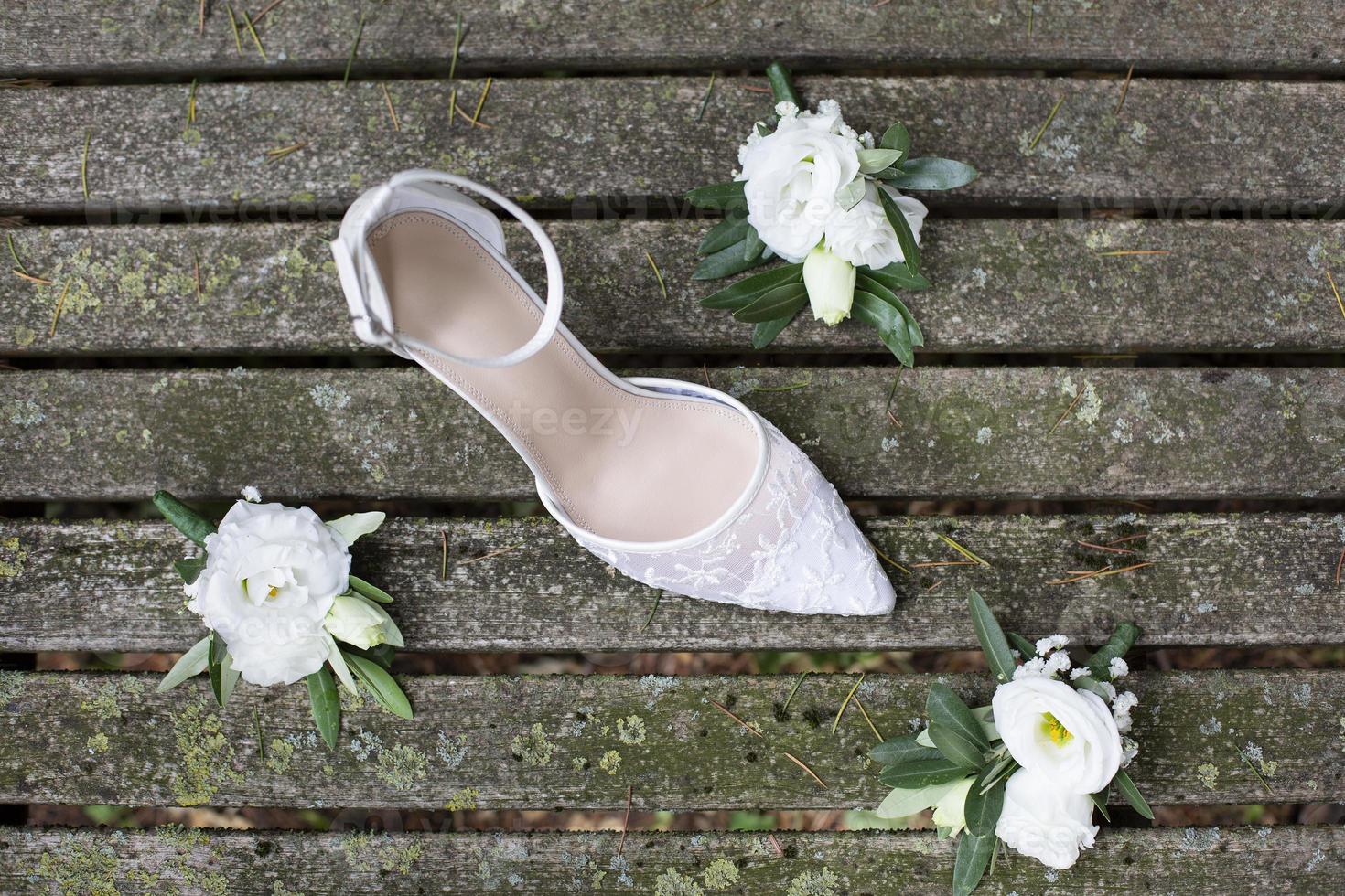 Zapato de boda blanco con flores blancas sobre tablas de madera antiguas foto