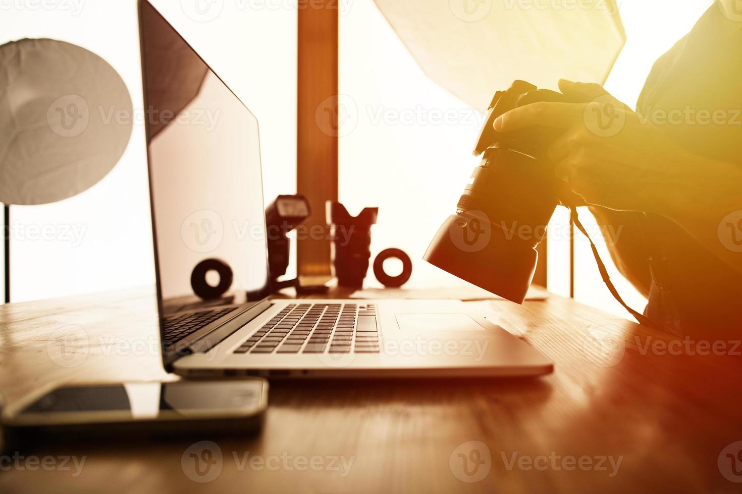 Retrato de un fotógrafo que trabaja en la PC en su estudio con una cámara en las manos foto