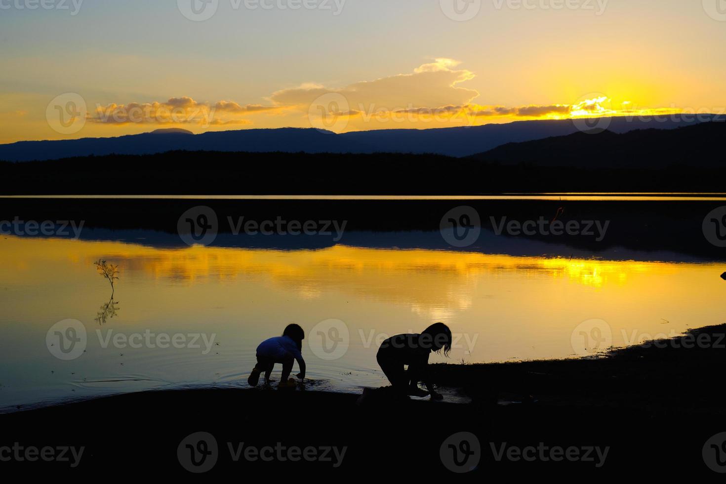 Siluetas de niños felices jugando en el lago al atardecer, depósito amphoe wang saphung loei Tailandia foto