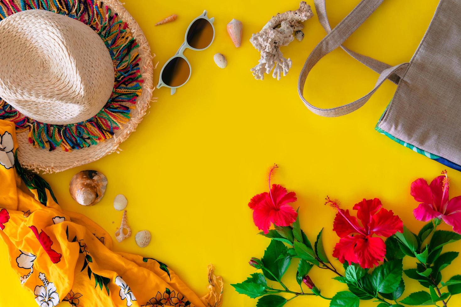 accesorios de playa para el viajero sobre fondo amarillo: gafas de sol, sombrero de paja, mochila, concha y flores de hibisco. concepto de turismo de playa. verano foto