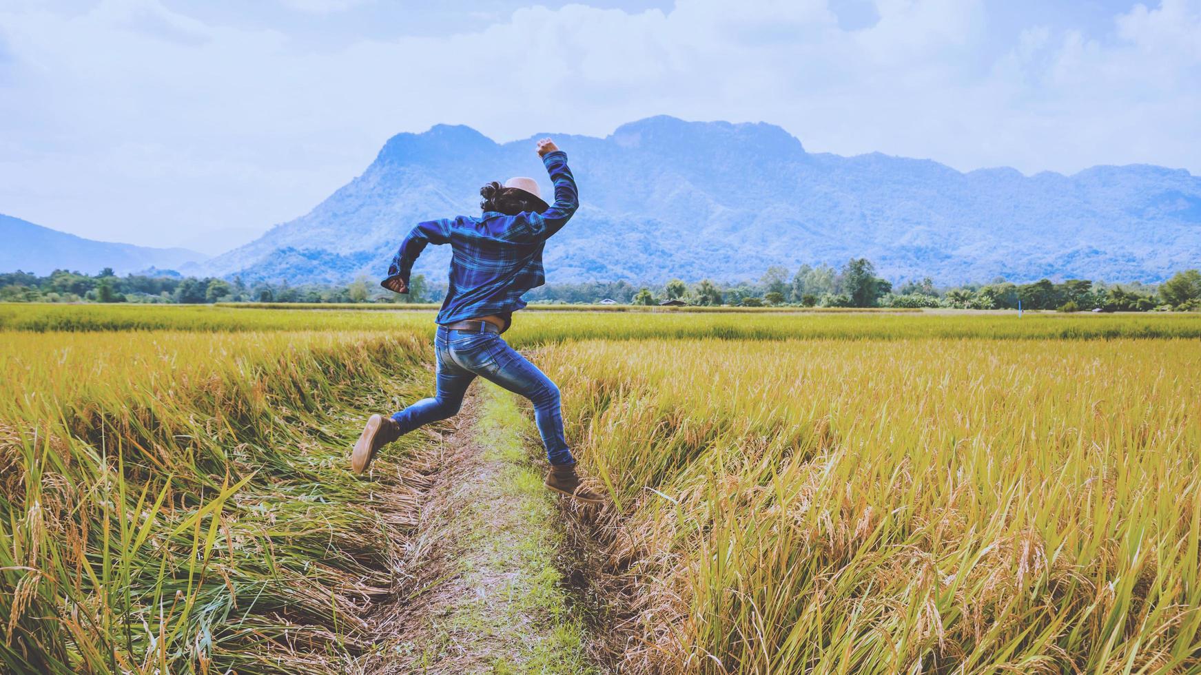 viaje de hombre asiático relajarse en las vacaciones. Saltar campo de montaña toque natural. salto de pie alegre arroz de campo medio. tailandia foto