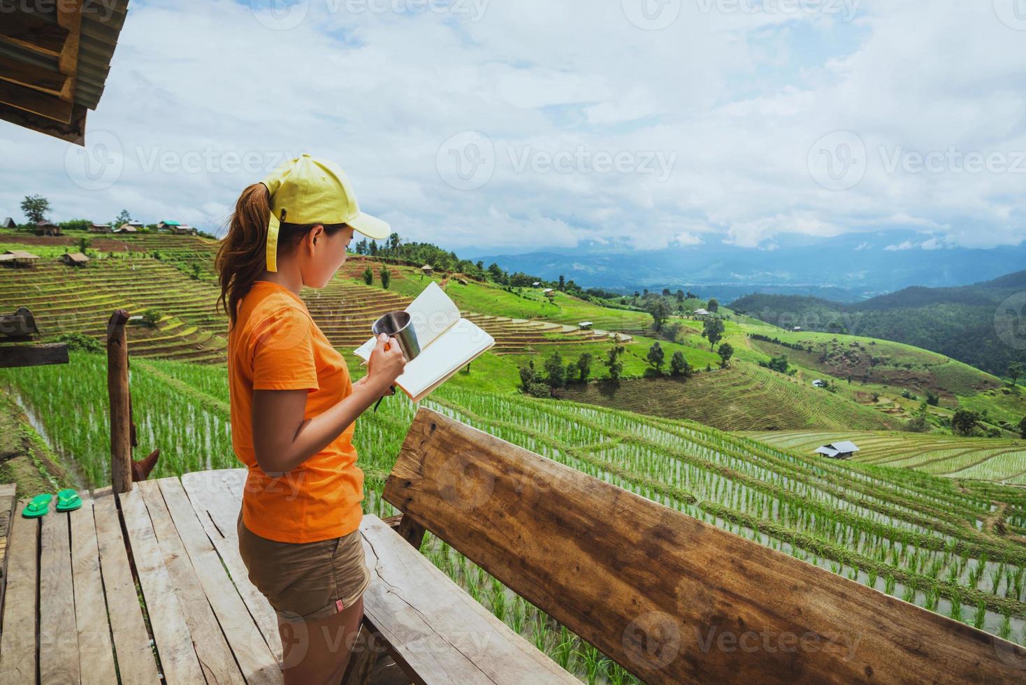 naturaleza de viaje de mujer asiática. viajar relajarse. de pie leyendo un libro en el balcón de la casa. en verano. foto