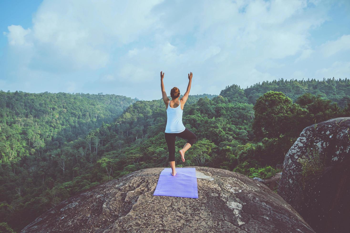 Asian women relax in the holiday. Play if yoga. On the Moutain rock cliff. Nature of mountain forests in Thailand photo