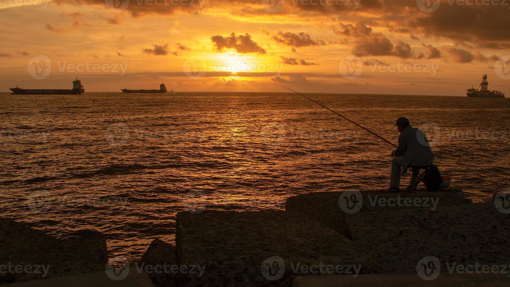 pescador al amanecer en la costa foto