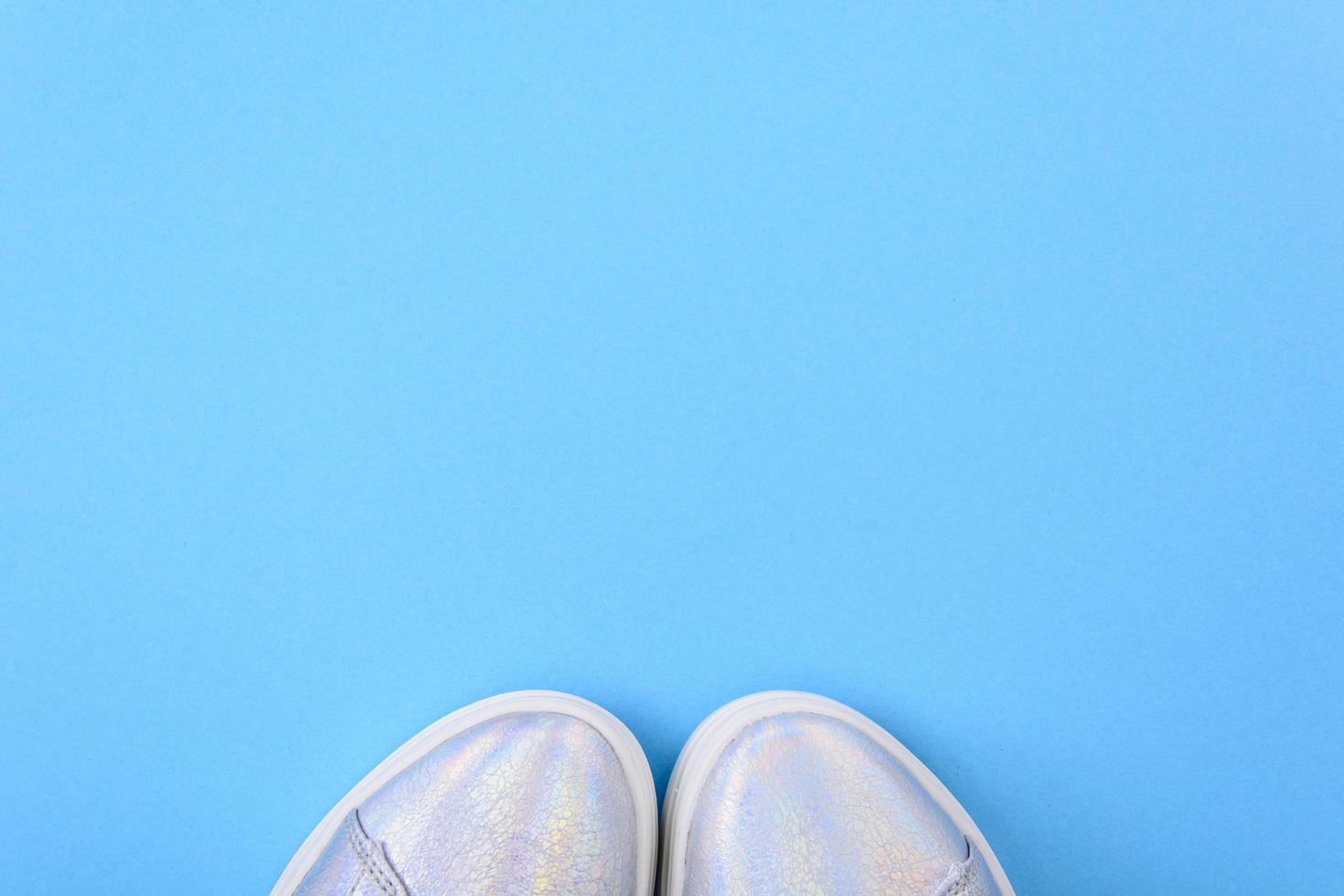 Zapatillas plateadas sobre un fondo azul con lugar para texto foto