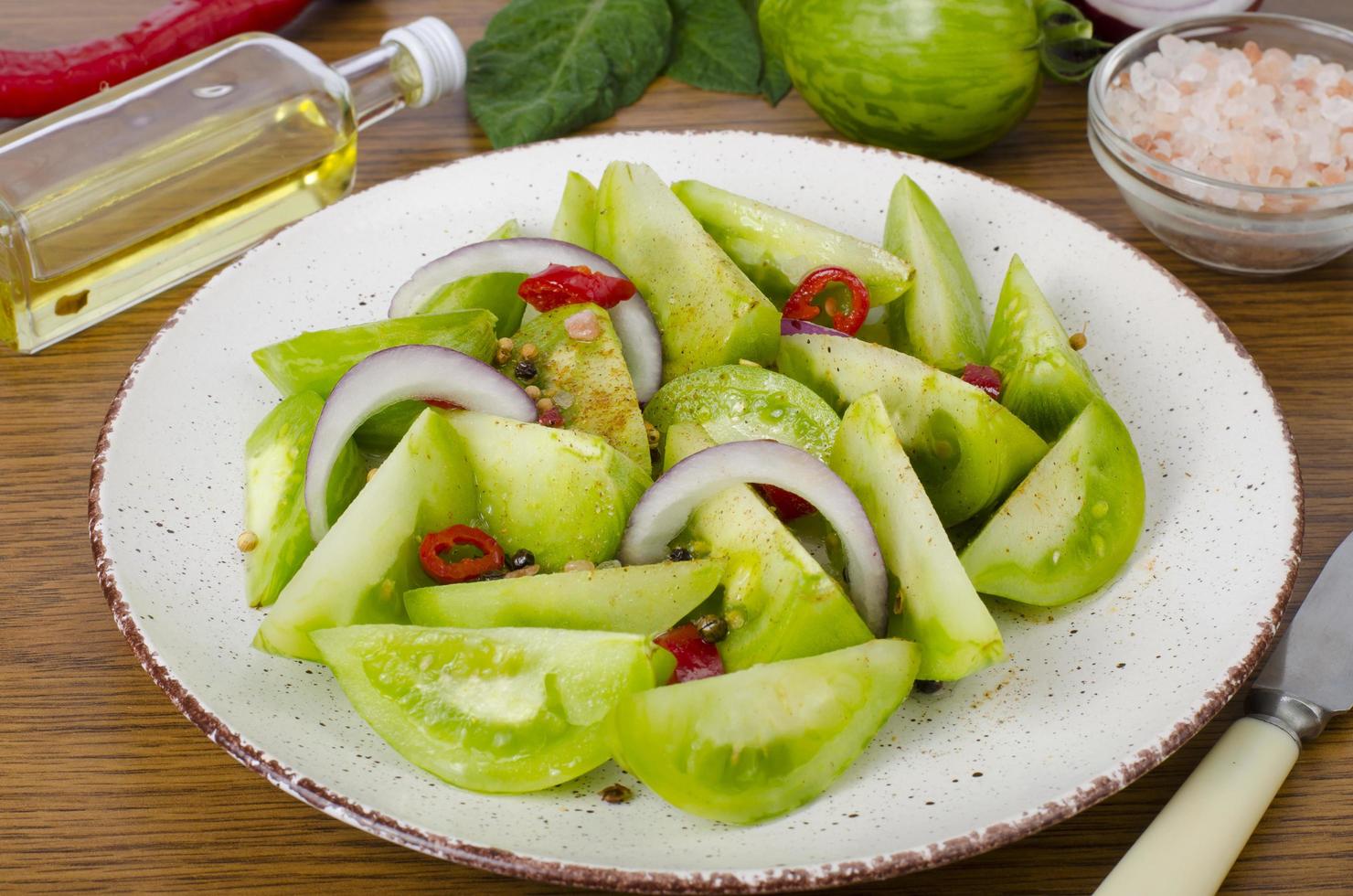 Appetizer of spicy pickled green tomatoes. Studio Photo. photo