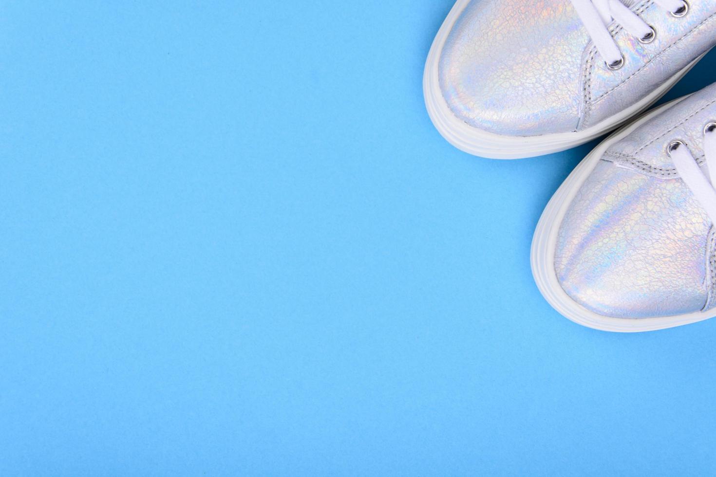 Silver sneakers on a blue background with place for text photo