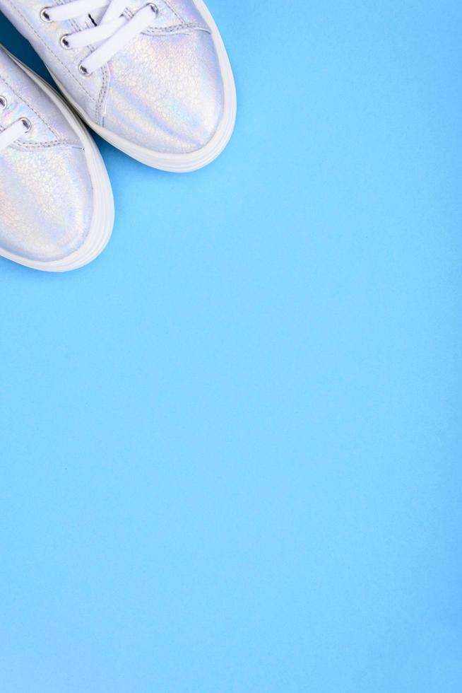 Silver sneakers on a blue background with place for text photo