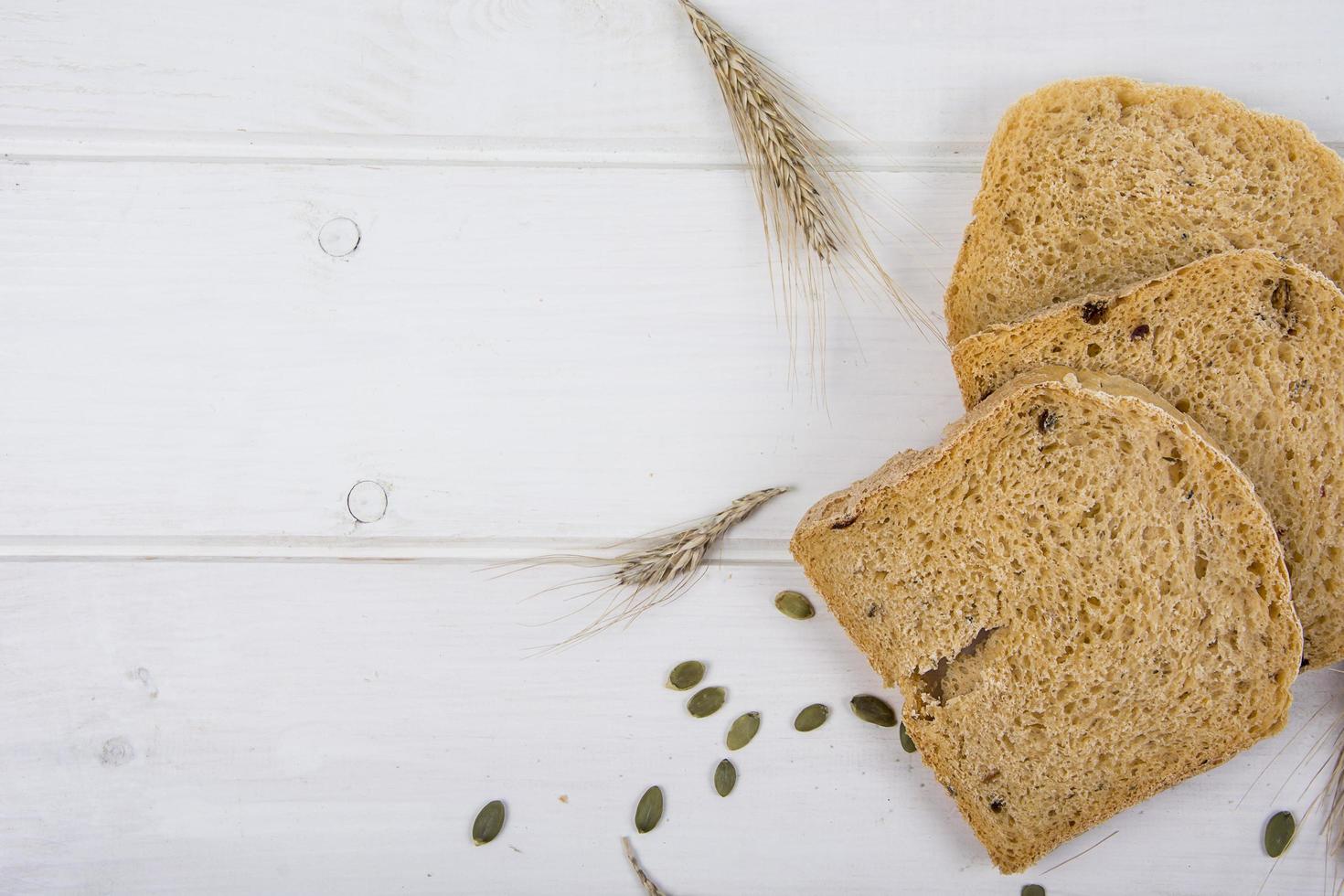 Pan rústico de levadura de trigo con semillas de calabaza sobre fondo de tablero de madera blanca foto