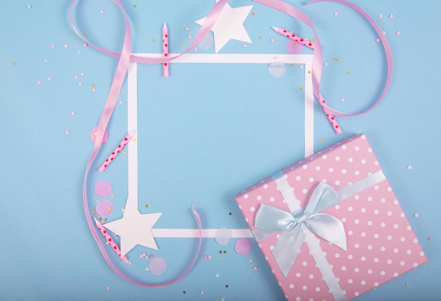 Party Holiday Background with ribbon, stars, birthday candles, gift box empty frame and confetti on blue background. photo