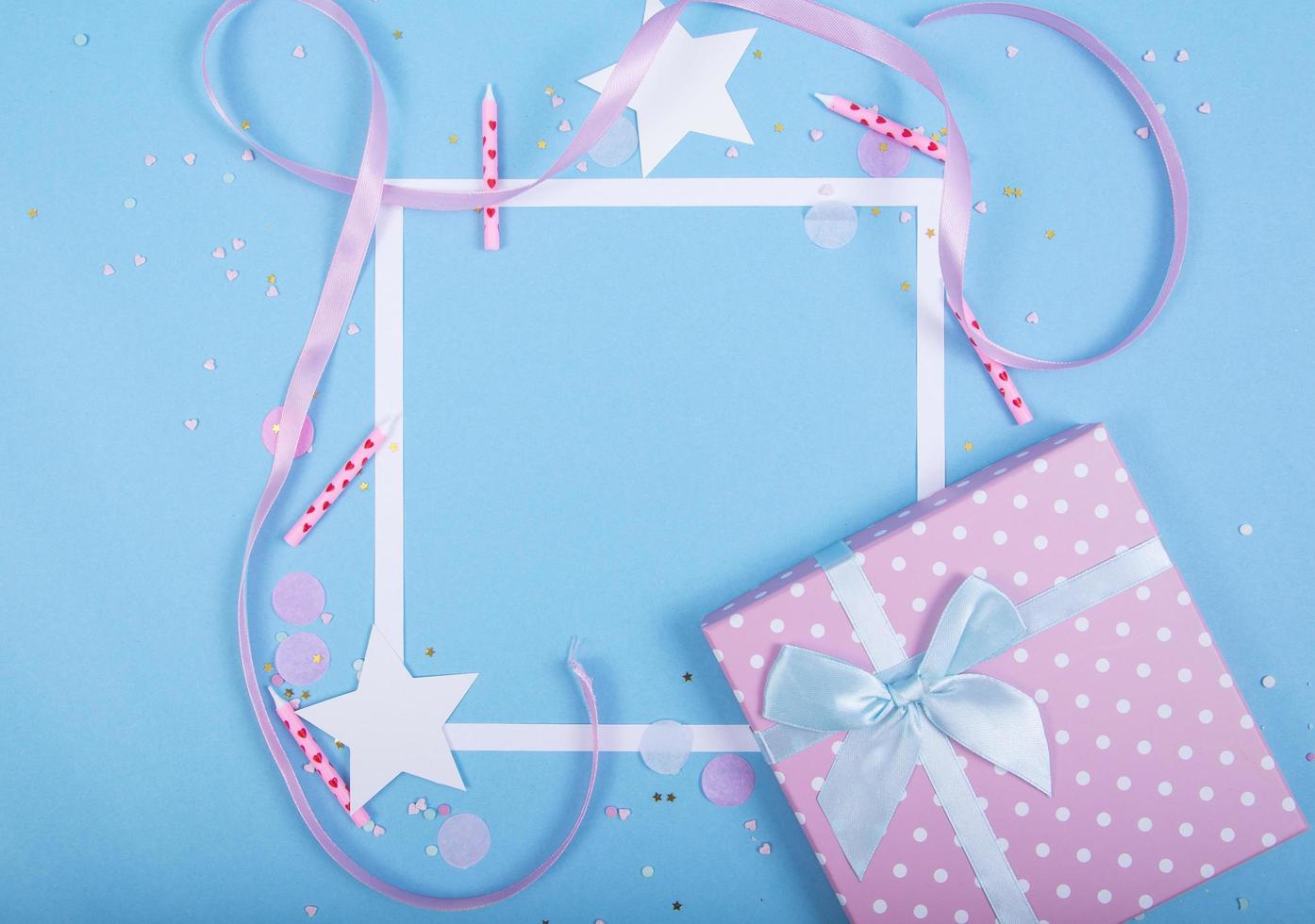 Party Holiday Background with ribbon, stars, birthday candles, gift box empty frame and confetti on blue background photo