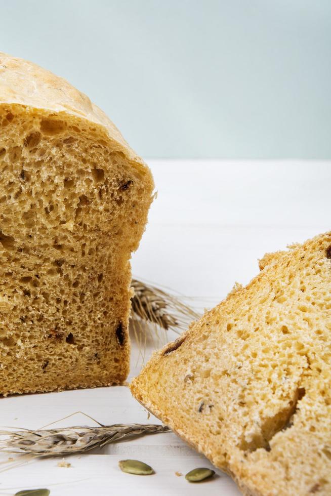 Pan rústico de levadura de trigo con semillas de calabaza sobre fondo de tablero de madera blanca foto