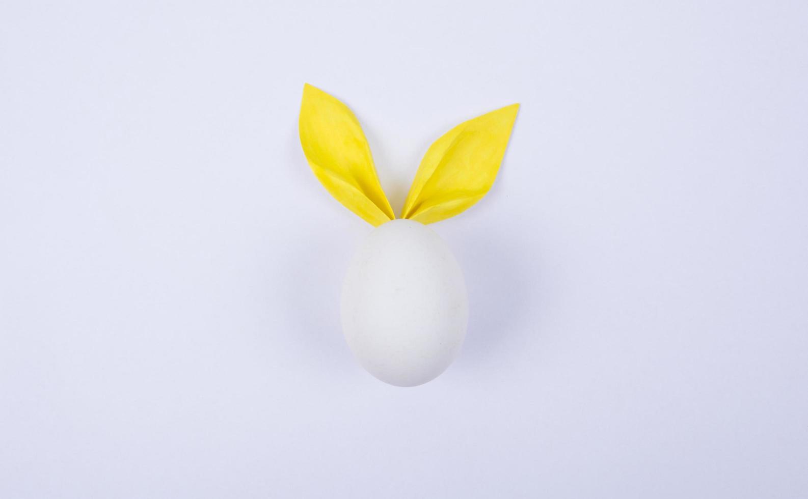 Egg with paper ears in the shape of an Easter bunny. Happy Easter Concept Card Postaer Background photo