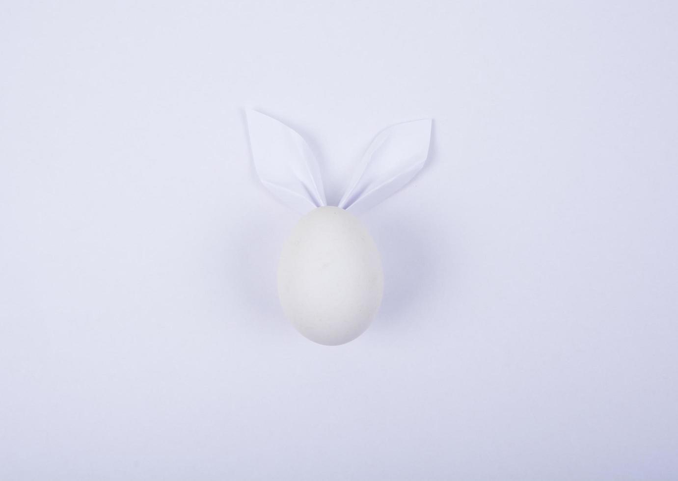 Egg with paper ears in the shape of an Easter bunny. Happy Easter Concept Card Postaer Background photo