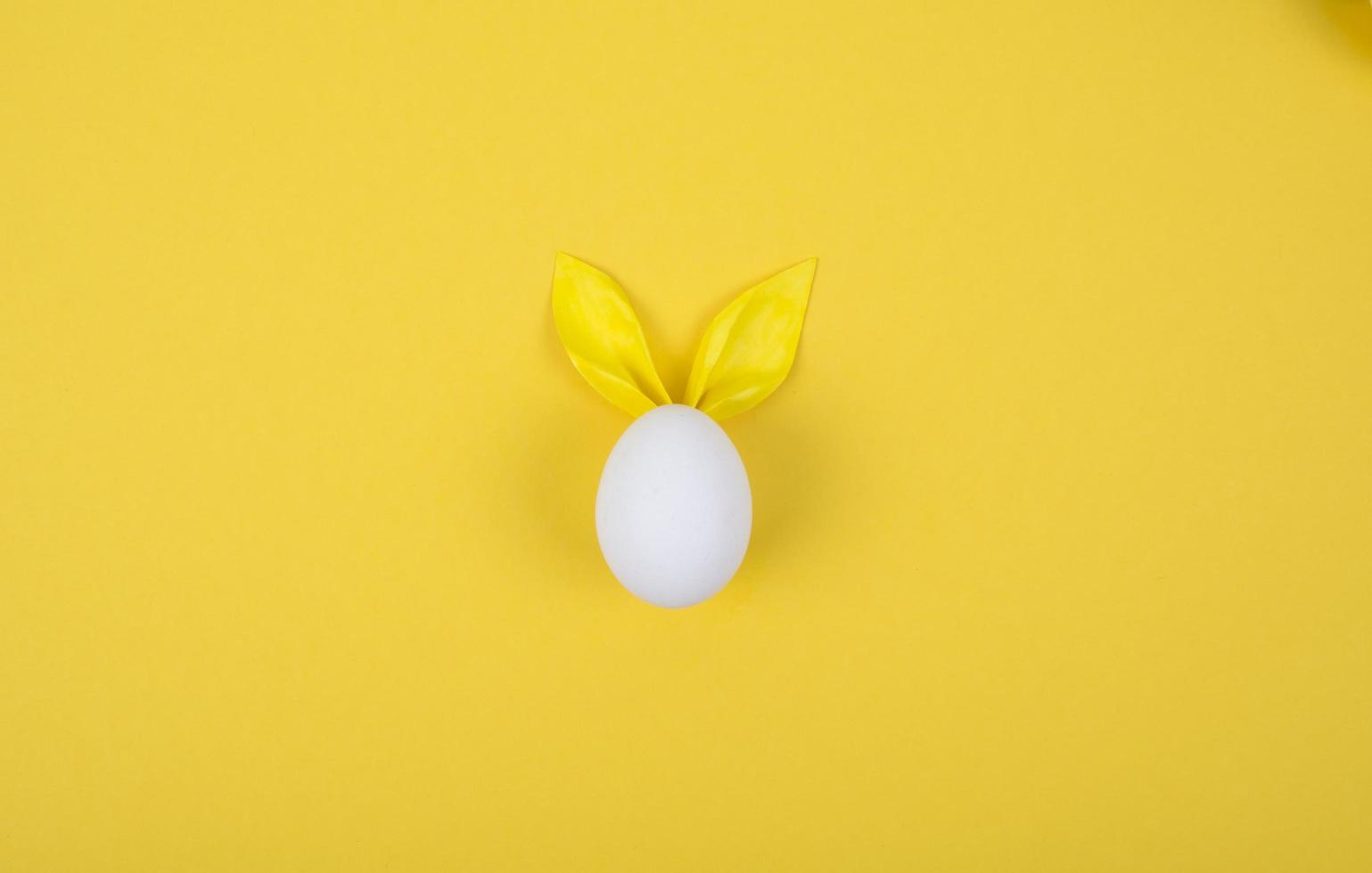 Egg with paper ears in the shape of an Easter bunny. Happy Easter Concept Card Postaer Background photo