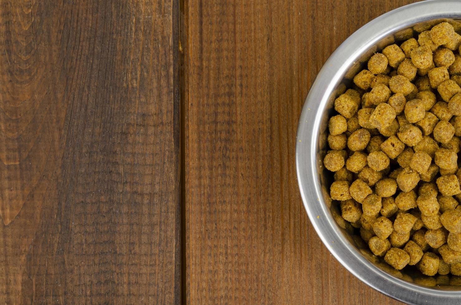 Comida seca para gatos en recipiente de metal sobre fondo de madera. foto de estudio