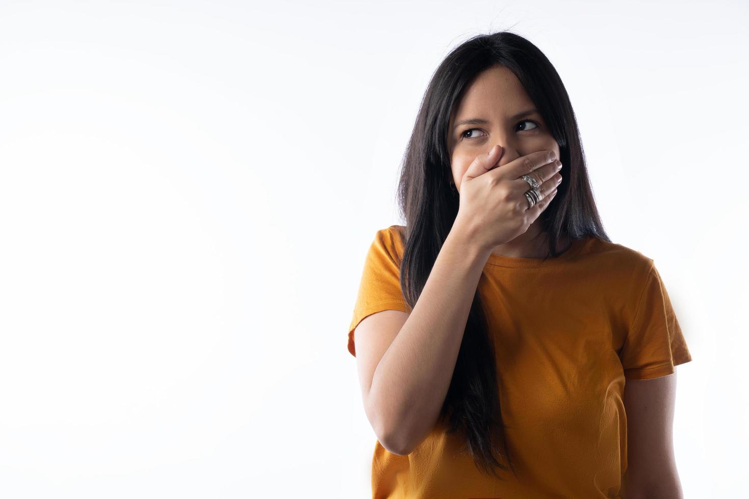 Close-up portrait of an attractive young woman covering her mouth, with mischievousness and looking to the side. photo