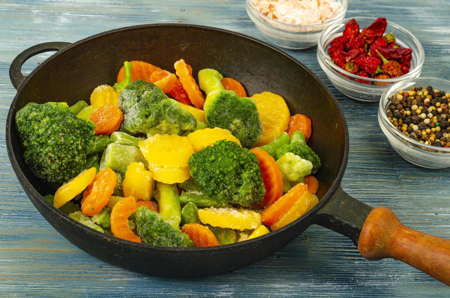 Vegetarian food. Mix of frozen fresh vegetables for frying on blue wooden background. Studio Photo