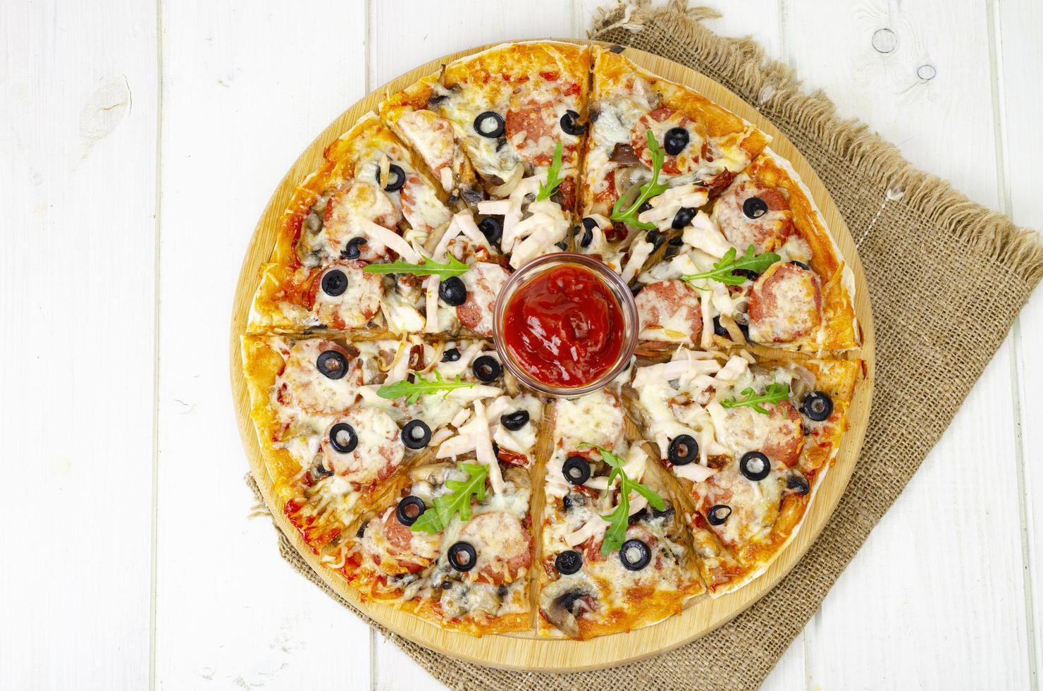 Homemade pizza with salami, ham and mozzarella on wooden table. Studio Photo