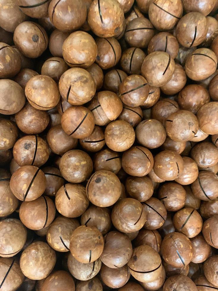 fondo, textura. nueces de macadamia con cáscara. Foto