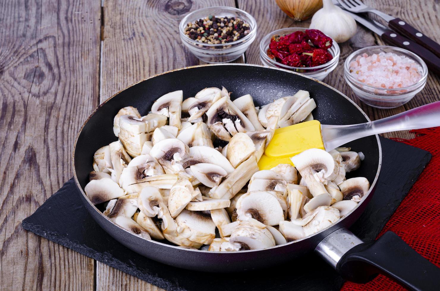 Sliced raw champignons in frying pan on wooden table. Studio Photo