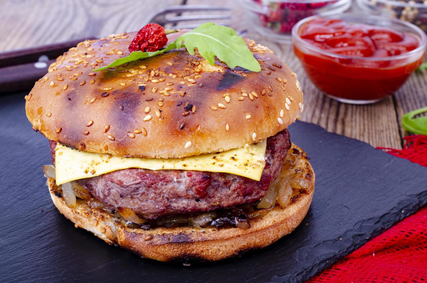 Homemade burger with sesame bun and ground beef on black stone. Studio Photo