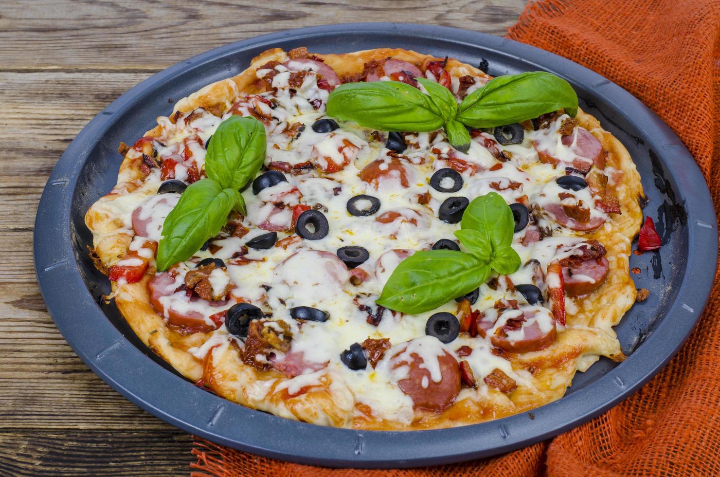 Homemade pizza with salami, mozzarella and olives photo