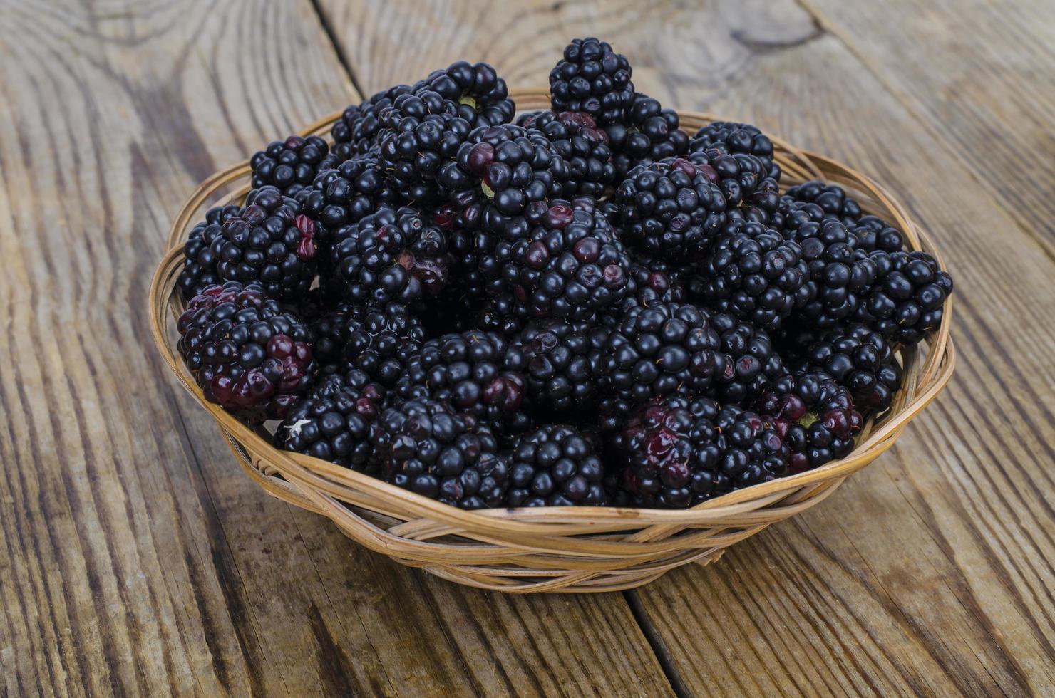 Ripe sweet black blackberries in wooden bowl photo